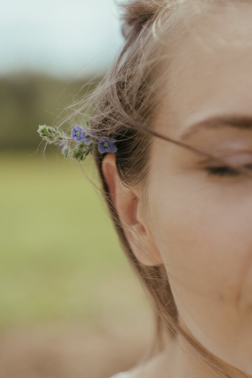 woman with blue flower on ear